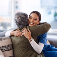 caretaker and elderly woman hug each other