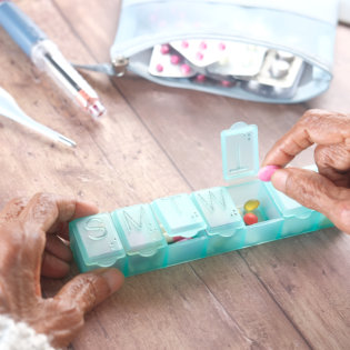 elderly women hands taking medicine from a pill box.