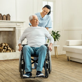 Cheerful positive caregiver moving a wheelchair