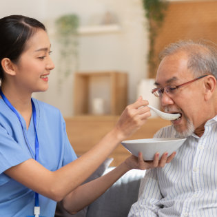 aide feeding an elderly man