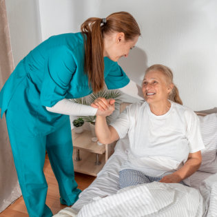 aide assisting ang elderly woman in getting up